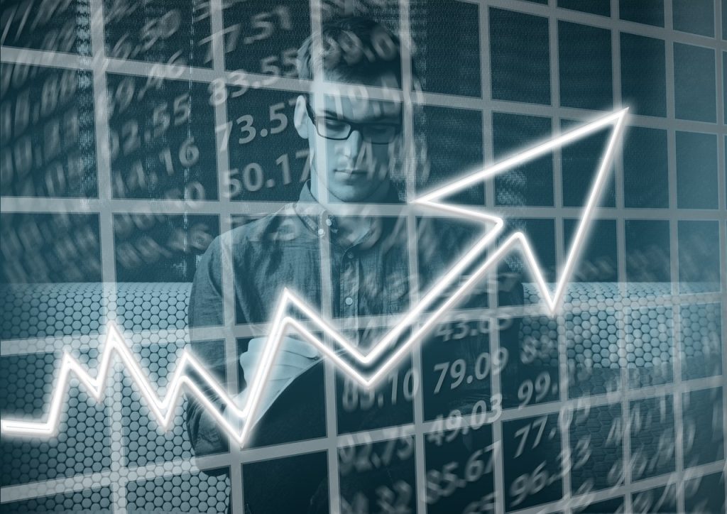 Man analysing data with an upward trending graph overlay, representing business growth and success